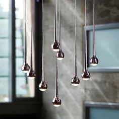 a bunch of silver balls hanging from a ceiling in a room next to a window