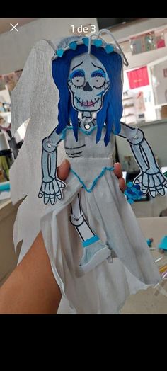 someone is holding up a paper doll with blue hair