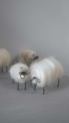 three woolly sheep are standing in the middle of a white room with black legs