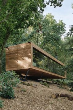 a wooden structure sitting on top of a hill surrounded by trees and bushes in the woods