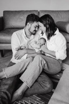 a man and woman sitting on the floor holding a baby