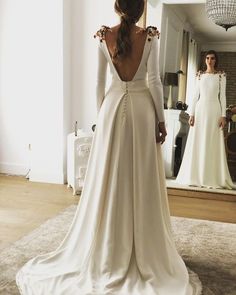 the back of a woman's wedding dress in front of a mirror