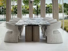 a dining table with chairs around it in front of large windows and palm trees outside