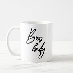 a white coffee mug with the word boss lady written on it in black ink, sitting on a marble surface