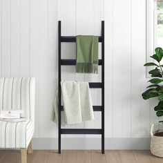 a towel rack with two towels on it next to a chair and potted plant