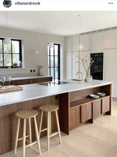 a large kitchen with two stools next to the counter top and an island in front of it