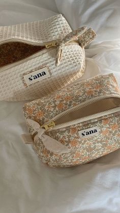 two purses sitting on top of a bed next to each other