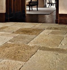 an open door leading into a living room with stone flooring and chairs in the background