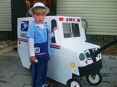 a young boy standing in front of a white cart with wheels on the street next to a house