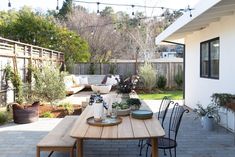 an outdoor dining area with wooden table and chairs, potted plants on the patio