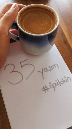 a person holding a cup of coffee on top of a paper with the number 35