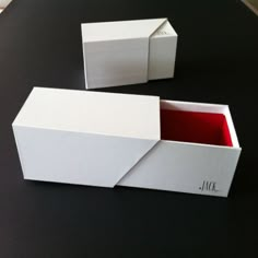 two empty boxes sitting on top of a black table with one open and the other closed