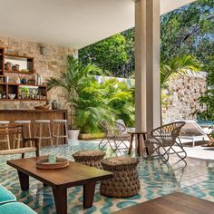 a living room filled with furniture and lots of plants on top of the floor next to a stone wall