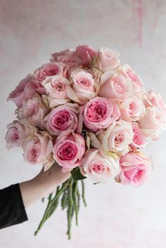 a person holding a bouquet of pink roses in their hand and the flowers are white