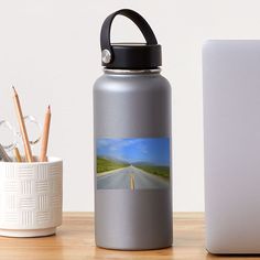 a water bottle next to a cup with pencils and an eraser on it