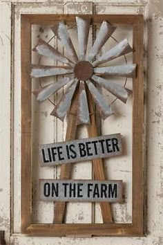 a sign that says life is better on the farm in front of a wooden windmill