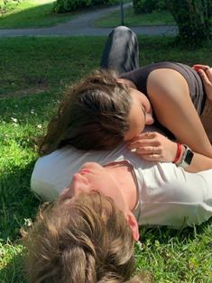 two people laying in the grass with their heads on each other