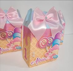 two boxes with pink bows and lollipops on them are sitting next to each other