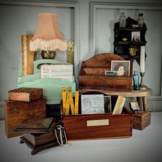 an assortment of wooden boxes, books and other items on a table with a lamp in the background