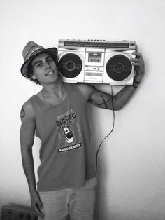 a young man holding up an old fashioned boombox to his face and listening to music