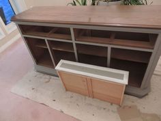 a large wooden cabinet sitting on top of a hard wood floor next to a potted plant