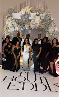 a group of people posing for a photo in front of a floral backdrop at a wedding