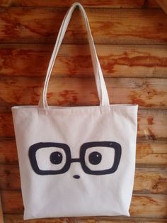 a tote bag with glasses on it hanging from the side of a wooden wall