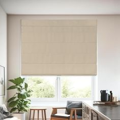 a living room filled with furniture and a window covered in roman blind shades on the windowsill