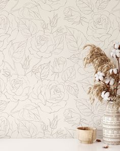 a vase filled with cotton flowers sitting on top of a table next to a wall paper