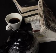 a stack of books sitting next to a cup of coffee on top of a table