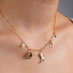 Drape yourself in the essence of the wild and refined with our Stampede Charm Necklace -- an ode to adventurous spirits and serene desert nights, featuring a delicate freshwater pearl and whimsical western charms, including a cowboy hat, boot, lucky horseshoe, and a twinkling star.  What is Gold Filled? Gold Filled is 5% gold by weight, which is 100x more gold than gold-plating. Gold filled is waterproof, hypoallergenic, tarnish-resistant, will last for years to come, and doesn't carry the hefty Western Baddie, Bachelorette Cowgirl, Western Necklaces, Nashville Bachelorette, Chapeau Cowboy, Lucky Horseshoe, Party Summer, Gold Charm Necklace, Summer Necklace