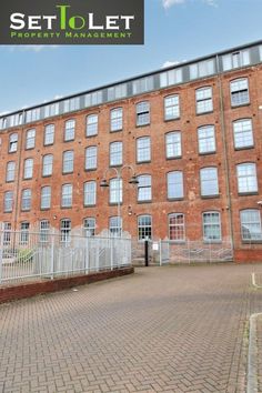 an apartment building with lots of windows on the side of it and a fenced in area