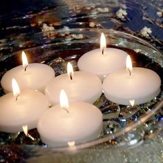 several lit candles are in a glass bowl