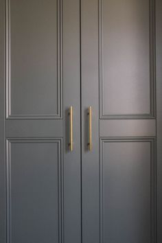 two gold handles on the doors of a gray closet