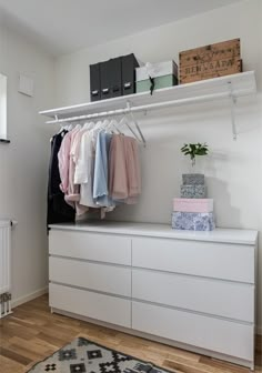 a white closet with clothes and boxes on the shelves