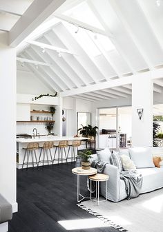 a living room filled with furniture next to a kitchen and dining room table on top of a hard wood floor