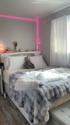 a bedroom with a large bed covered in fluffy blankets and pillows, along with a teddy bear