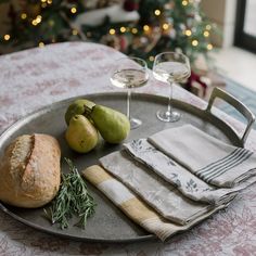 a plate with bread, pears and two glasses of wine sitting on top of it