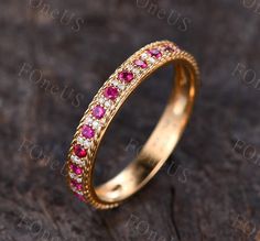 a gold ring with pink and white stones on it, sitting on a wooden surface