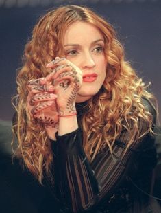 a woman holding her hand up to her face with tattoos on it's hands