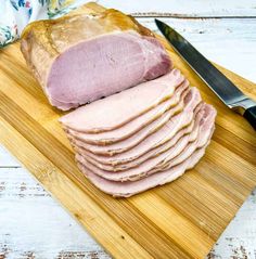 sliced ham sitting on top of a cutting board next to a knife