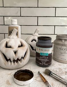 some pumpkins are sitting on a table with paint and other items around them,