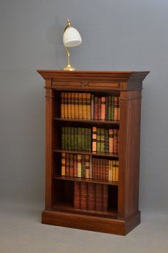 an old wooden bookcase with many books on it and a lamp sitting on top