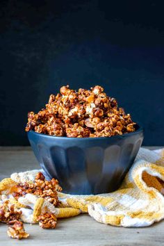 a blue bowl filled with caramel popcorn on top of a yellow and white towel