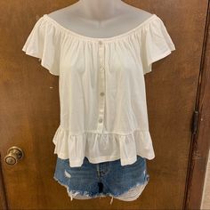 New With Tags, No Flaws. Size Medium Fits Tts But Could Really Fit Small-Medium Comfortably. Purchased From Rue21. This Cute Blouse Comes In Ivory And Features A Faux Button Front Design With Pearl-Like Buttons, Ruffle Trim Along The Hem, An Off The Shoulder Neck With A Layered Flounce Sleeve And Elastic Banding Through The Top For Easy Shoulder Placement. Material: Made From A Super Soft Cotton Blend Fabric. Slightly Stretchy And Runs A Little Thicker Than A Regular Tee While Still Maintaining Loose Shirts For Women Style, White Summer Tops With Button Closure, White Top With Button Closure For Day Out, White Tops With Button Closure For Day Out, Summer Tops With Buttons For Day Out, Casual Cream Tops For Daytime, Off The Shoulder Blouse, Cream Button-up Top For Summer, Cream Top With Button Closure For Day Out