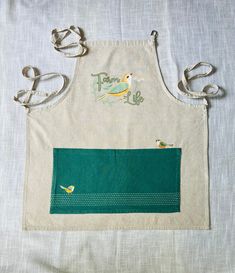 an apron with two birds on it sitting on top of a white cloth covered table