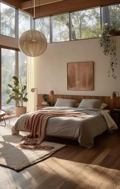 a bedroom with wooden floors and large windows overlooking the trees in the distance is shown