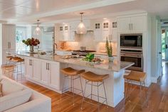 a large kitchen with white cabinets and wooden floors