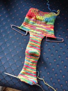 a knitted sock sitting on top of a piece of blue fabric next to a pair of scissors