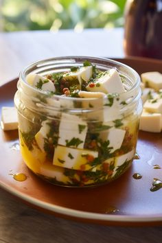 a glass jar filled with food sitting on top of a wooden table next to sliced cheese